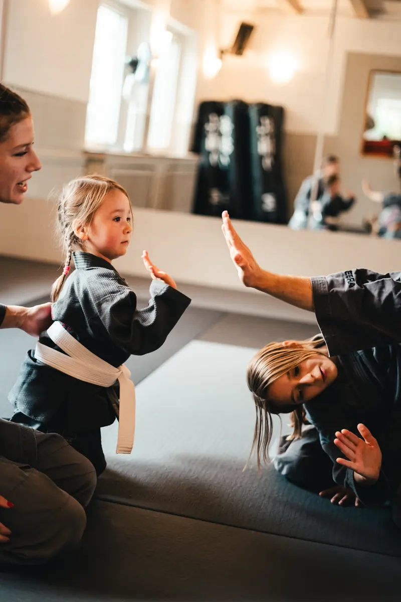 Kleines Mädchen im Gi beim Kindertraining, die Hand zum Abklatschen erhoben