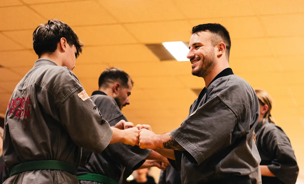 Randori-Pro Tegel: Zwei Sportler im Gi stoßen lachend die Fäuste aneinander