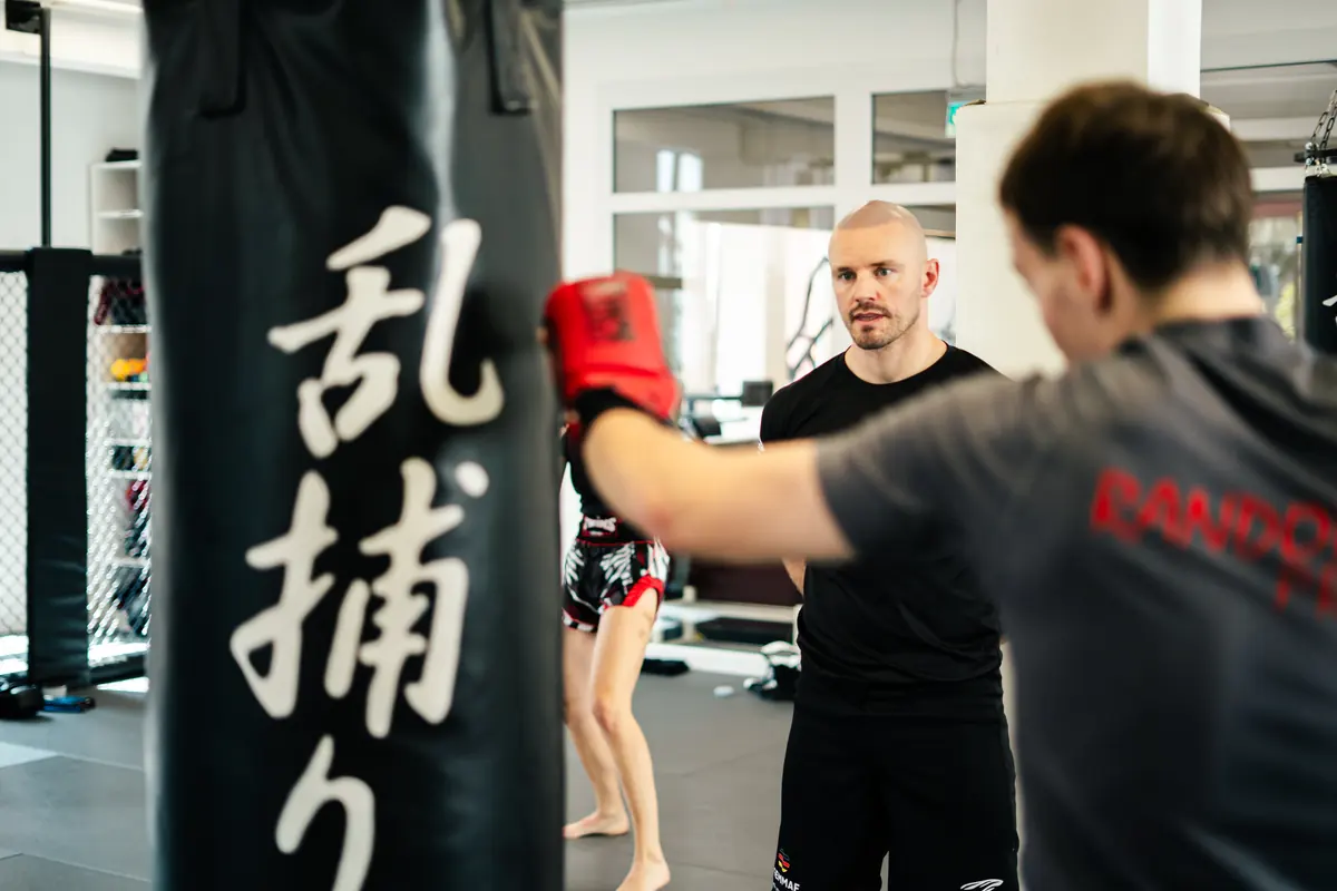 Personal Training: Ein Trainer beobachtet konzentriert die Schlagtechnik seines Trainingspartners
