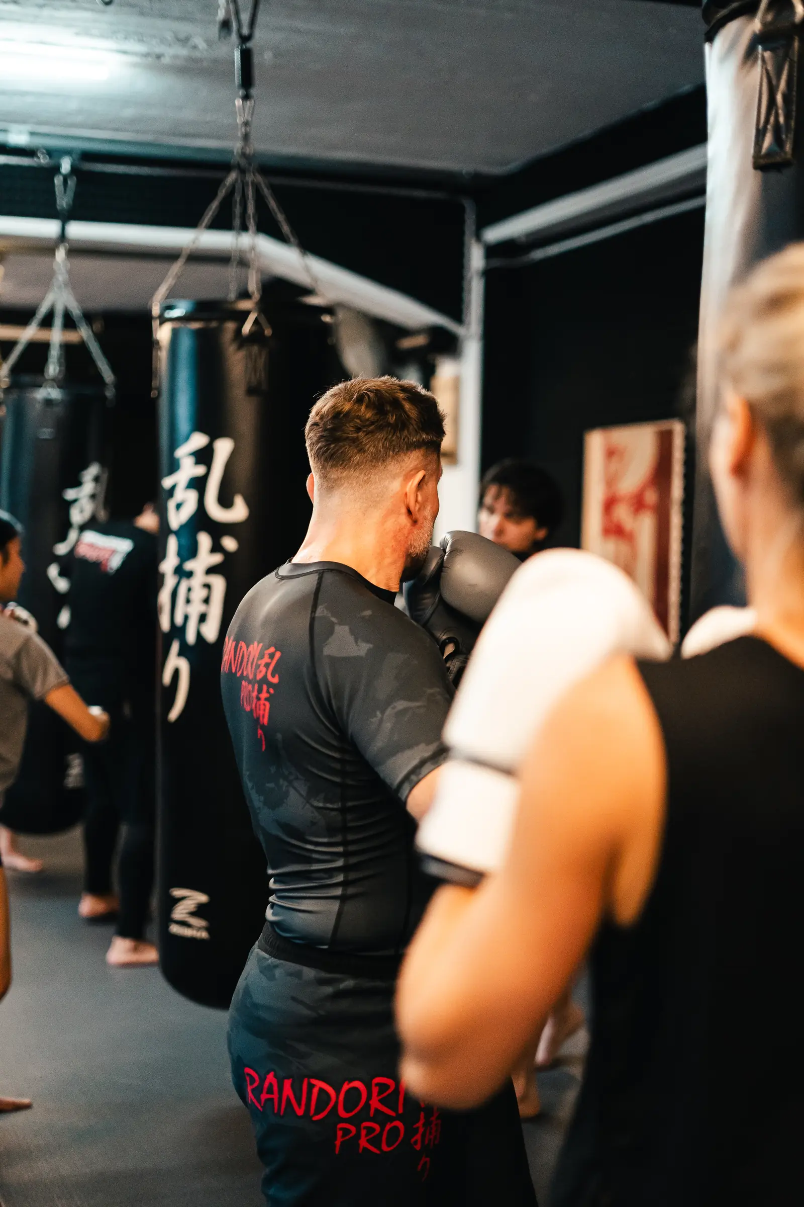 Sandsackarbeit im Erwachsenentraining bei Randori-Pro: Sportler mit Boxhandschuhen zwischen den Sandsäcken