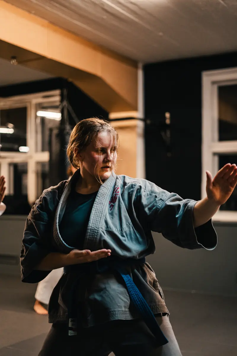 Frau im Kampfanzug in Abwehrstellung beim Karate-Training