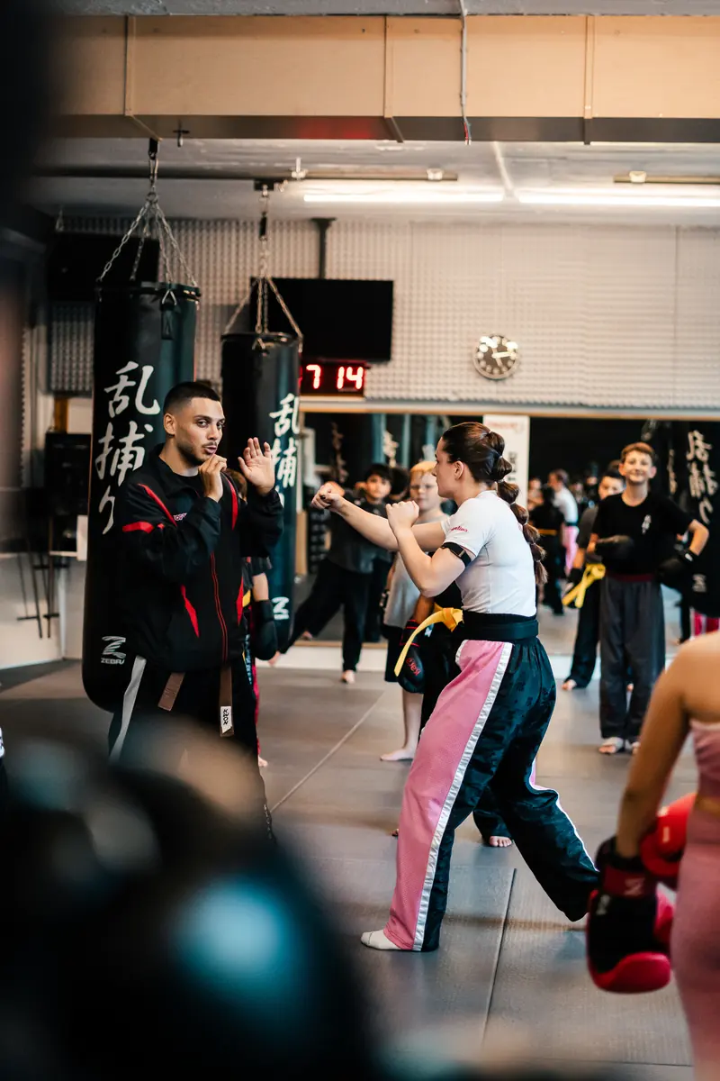 Trainer zeigt einer Teilnehmerin im Kickbox-Training eine Schlagtechnik