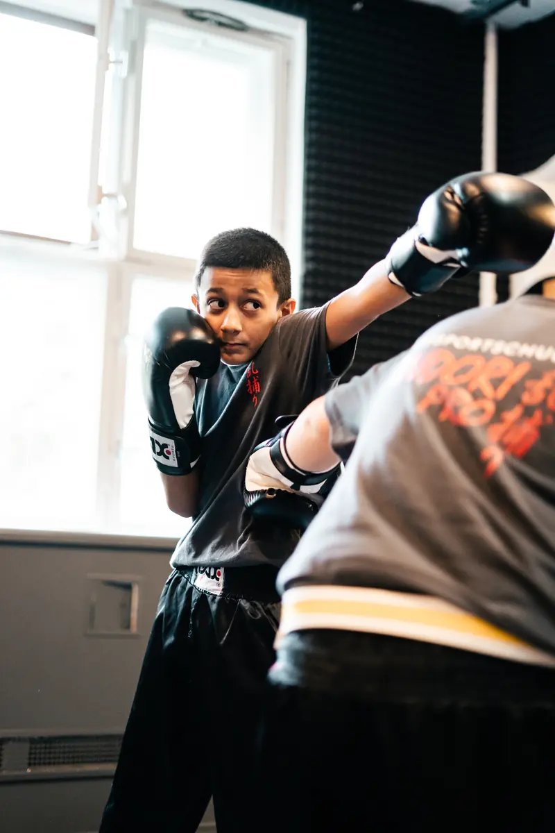 Junge mit Boxhandschuhen in Deckung gegenüber seinem Trainingspartner